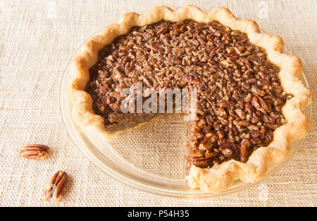 Torta alle noci pecan in una torta chiara la piastra con una fetta rimosso da esso Foto Stock