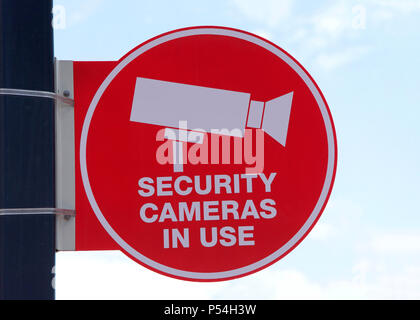 Rosso le telecamere di sicurezza di utilizzare il segno su un palo con blu cielo nuvoloso sfondo. Avvertimento sarebbe essere criminali le loro azioni saranno registrate. Foto Stock