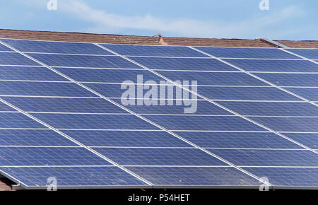 Grandi pannelli solari sul legno di un tetto di scandole, blu cielo nuvoloso sfondo soprastante. Pannelli solari fotovoltaici di assorbire la luce solare come una fonte di energia a gen. Foto Stock