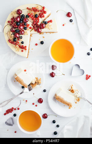 Servita tabella con New York cheesecake con bacche di colore bianco su un tavolo di legno. Angolo di visione. Foto Stock