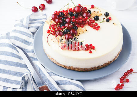 New York cheese cake con bacche di colore bianco su un tavolo di legno. Angolo di visione. Foto Stock