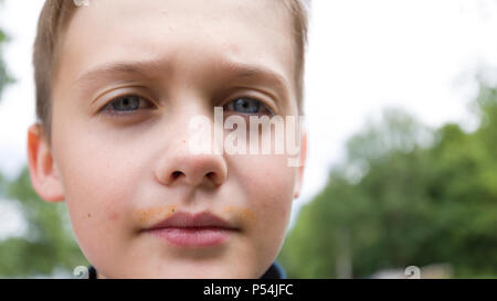 Extreme close up volto ritratto di blue eye 10 anno vecchio ragazzo alla ricerca seria e fiducioso in telecamera Foto Stock