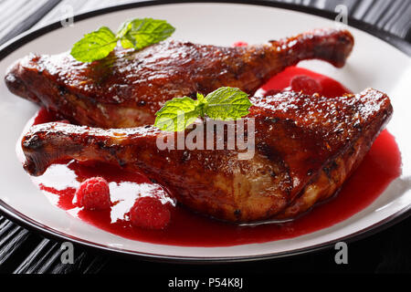 L'anatra al forno gamba servito con salsa di lamponi e menta su una piastra sul tavolo. Gastronomia natalizia. orizzontale Foto Stock