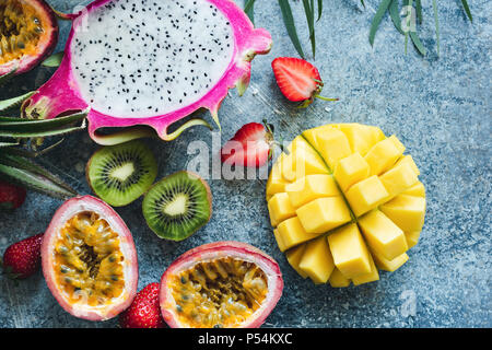 Mango, pitaya, kiwi, fragola e frutto della passione. Frutti tropicali su sfondo di calcestruzzo Foto Stock