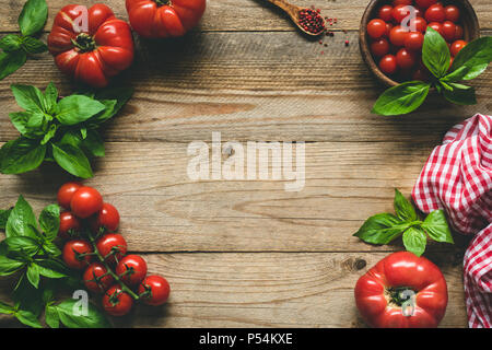 Rustico sfondo alimentare. Cimelio di pomodori, spezie e basilico sul legno. Vista da sopra con copia spazio per il testo Foto Stock