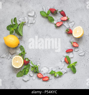 Mint, ghiaccio, fragole e limone. Estivo rinfrescante lemonade ingredienti come una corona sul cemento grigio Sfondo con copia spazio per il testo Foto Stock