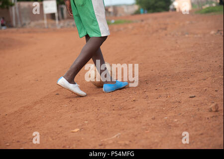 Mali, Africa - circa agosto 2009 - nero piccolo ragazzo giocando a calcio vicino a Bamako nella sabbia rossa Foto Stock