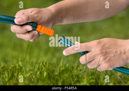 Mani il collegamento dei tubi flessibili per irrigazione del prato o giardino, primo piano Foto Stock