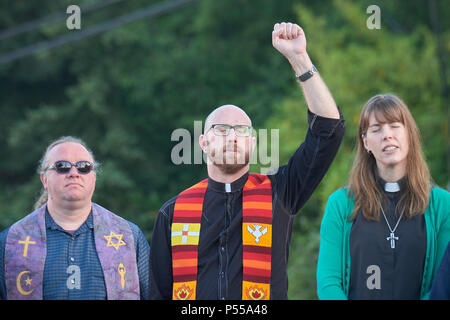 Seatac, Washington, Stati Uniti d'America. 24 Giugno, 2018. Clero pregare al di fuori del recinto che circonda la Federal centro di detenzione a Seatac, Washington, inizio giugno 24 durante una veglia di preghiera a sostegno di genitori immigrati all interno del carcere che sono stati separati dai loro figli. La veglia è stato sponsorizzato dal Regno chiesa metodista. Credito: Paul Jeffrey/Alamy Live News Foto Stock