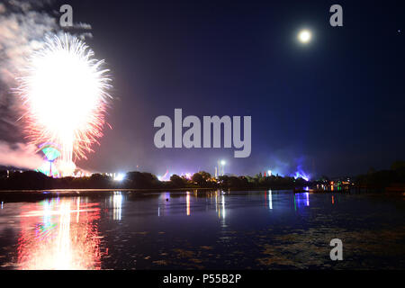 Newport, Isle of Wight, Regno Unito. Il 24 giugno 2018. Fuochi d'artificio e una nei pressi di luna piena araldo della fine dell'ultimo giorno dell'Isola di Wight Festival come la domenica notte il rivestimento padiglione band 'Killer' gioca sul palco principale, visto nella distanza di luci blu. Fotografia scattata dalla riva del fiume Medina a Newport, Isle of Wight, 24 giugno 2018. Credito: Matteo Blythe/Alamy Live News Foto Stock