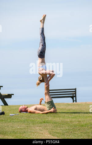 Aberystwyth, Galles. 25 GIU, 2018. Regno Unito: Meteo Meteo REGNO UNITO: molto adatta coppia giovane pratica loro Acro Yoga ( un mix di acrtobatics e yoga) vicino al castello in Aberystwyth, su un altro ancora scintillante la giornata di caldo sole ininterrotta. Il Regno Unito è il titolo in un mini ondata di caldo con temperature meteo per colpire 29º o 30º Celsius entro la metà della settimana foto © Keith Morris / Alamy Live News Foto Stock