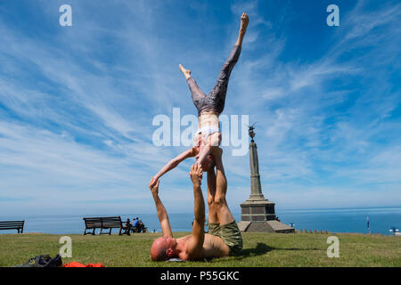 Aberystwyth, Galles. 25 GIU, 2018. Regno Unito: Meteo Meteo REGNO UNITO: molto adatta coppia giovane pratica loro Acro Yoga ( un mix di acrtobatics e yoga) vicino al castello in Aberystwyth, su un altro ancora scintillante la giornata di caldo sole ininterrotta. Il Regno Unito è il titolo in un mini ondata di caldo con temperature meteo per colpire 29º o 30º Celsius entro la metà della settimana foto © Keith Morris / Alamy Live News Foto Stock