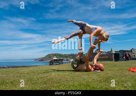 Aberystwyth, Galles. 25 GIU, 2018. Regno Unito: Meteo Meteo REGNO UNITO: molto adatta coppia giovane pratica loro Acro Yoga ( un mix di acrtobatics e yoga) vicino al castello in Aberystwyth, su un altro ancora scintillante la giornata di caldo sole ininterrotta. Il Regno Unito è il titolo in un mini ondata di caldo con temperature meteo per colpire 29º o 30º Celsius entro la metà della settimana foto © Keith Morris / Alamy Live News Foto Stock