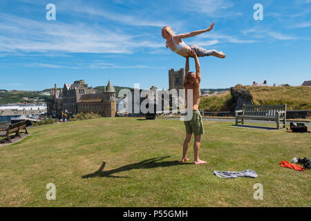 Aberystwyth, Galles. 25 GIU, 2018. Regno Unito: Meteo Meteo REGNO UNITO: molto adatta coppia giovane pratica loro Acro Yoga ( un mix di acrtobatics e yoga) vicino al castello in Aberystwyth, su un altro ancora scintillante la giornata di caldo sole ininterrotta. Il Regno Unito è il titolo in un mini ondata di caldo con temperature meteo per colpire 29º o 30º Celsius entro la metà della settimana foto © Keith Morris / Alamy Live News Foto Stock