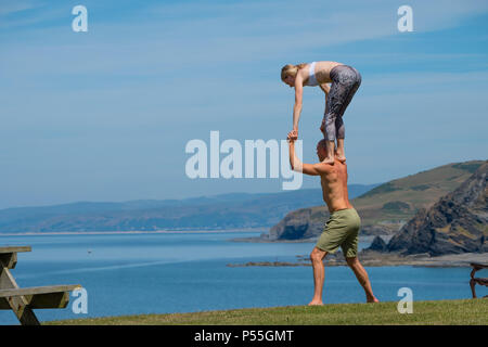 Aberystwyth, Galles. 25 GIU, 2018. Regno Unito: Meteo Meteo REGNO UNITO: molto adatta coppia giovane pratica loro Acro Yoga ( un mix di acrtobatics e yoga) vicino al castello in Aberystwyth, su un altro ancora scintillante la giornata di caldo sole ininterrotta. Il Regno Unito è il titolo in un mini ondata di caldo con temperature meteo per colpire 29º o 30º Celsius entro la metà della settimana foto © Keith Morris / Alamy Live News Foto Stock