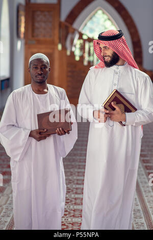 Due religiosa musulmana uomo a camminare insieme all'interno della moschea Foto Stock