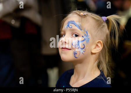 Carino bimba bionda con face painting. Blue astratto schema a fiocco di neve da acquerello su bambini faccia. Adorabile bambino con disegni colorati. Bambini Foto Stock