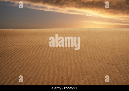 Il riscaldamento globale del concetto. Lonely dune di sabbia sotto drammatico tramonto Cielo a siccità il paesaggio del deserto. Foto Stock