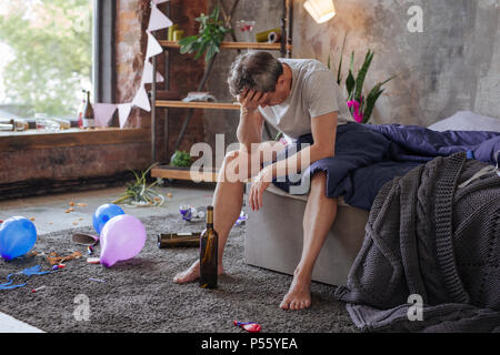 Sconvolto uomo maturo avente i postumi della sbornia Foto Stock