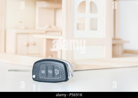 Chiavi auto con casa in legno modello in background. Scelta di byuing necessità di base. Decisione della priorità o necessità primaria Foto Stock
