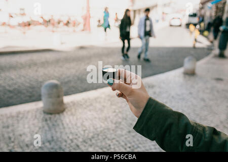 Una donna di mano trattiene un vetro a base di cioccolato in cui il tradizionale liquore portoghese è colorato di nome Ginjinha e preparare per bere Foto Stock