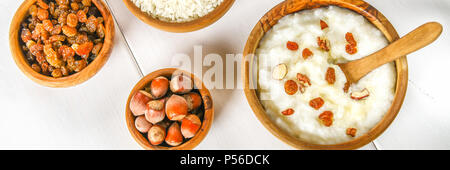 Latte di riso porridge con noci e uvetta in ciotole di legno su un bianco tavolo in legno Foto Stock