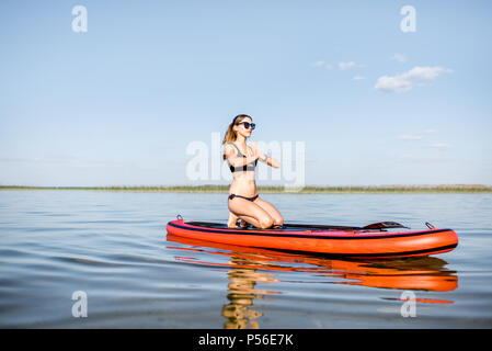 Donna fare yoga sulla paddleboard Foto Stock