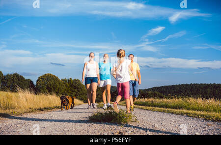 Famiglia a piedi il loro cane su un percorso sterrato Foto Stock