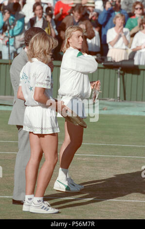 Steffi Graf nella foto mentre tiene il suo trofeo vincitori e Martina Navratilova con la sua corridori trophy. Tra di essi è Alan Mills, Wimbledon arbitro. Steffi Graf batte corrente 6 volte campione in carica Martina Navratilova, a vincere il torneo di Wimbledon Ladies Singles finale del 2 luglio 1988. Dopo Graf ha preso un 5-3 portano nel primo set, Navratilova ha vinto sei giochi dritto consentendogli di vincere il primo set e prendere un 2-0 portano nel secondo set. Graf tornò quindi vincendo 12 del prossimo 13 giochi e la partita. Steffi Graf il primo di 7 Wimbledon singles titolo vince. 1988, 1989, 1991, 1992, 1993, 1995 Foto Stock