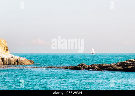 Due piccole isole di roccia in mare aperto collegato con stretto istmo. Lonely barca a vela con vele bianche . Bellissimo paesaggio romantico, seascape. Foto Stock