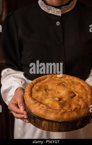 Torta di patate formaggio a base di carne e verdure. Pane appena sfornato la torta in mani della donna in uniforme Foto Stock