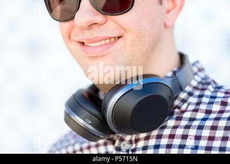Close up Uomo con occhiali da sole e le cuffie di fantasia sul suo collo Foto Stock