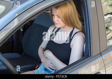 Giovane donna femmina driver con stomachache in auto Foto Stock