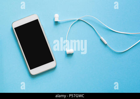 Vista superiore mockup smartphone e auricolari su sfondo blu. Lay piatto. Spazio per la copia Foto Stock