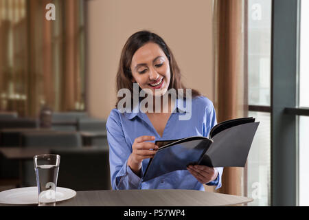 Imprenditrice rivista di lettura sul tavolo Foto Stock