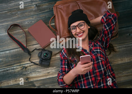 Femmina azienda turistica phone giacente su sfondo di legno Foto Stock