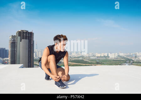 Giovane uomo asiatico tie sport lacci delle scarpe prima di eseguire all'aperto Foto Stock