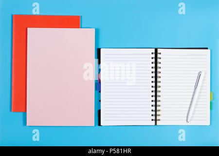 Aprire il notebook con penne bianche e colorate notebook su sfondo blu Foto Stock