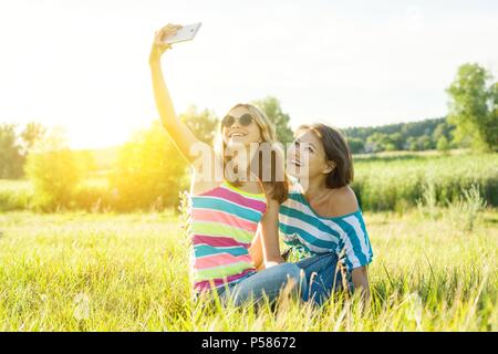 Ritratto di bella adulto madre e figlia adolescente facendo una selfie utilizzando uno smart phone e sorridente. Foto Stock