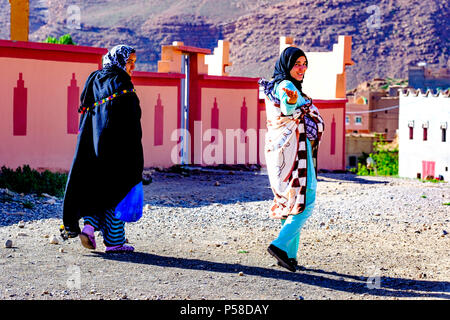 Due giovani donne in abito tradizionale a piedi nel villaggio di Tamtetoucht ai piedi dell'Alto Atlante in Marocco Foto Stock