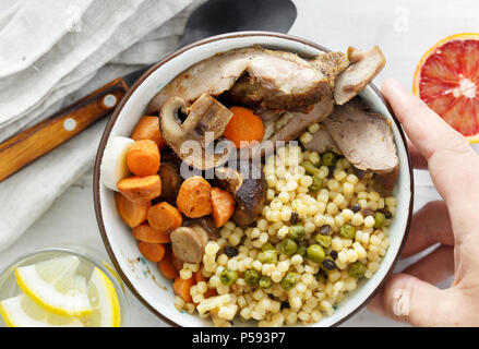 Cibo sano e tavolo per la cena del concetto. Mix di orzo e frumento porridge con la Turchia al forno, le carote e i funghi in una terrina bianco sul tavolo di legno, vista dall'alto Foto Stock