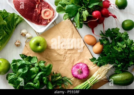 Il telaio dal sacchetto di carta e impostare il cibo sano su bianco tavolo in legno. Vista dall'alto. Lay piatto. Concetto acquistare cibo sano Foto Stock