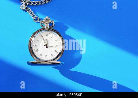 Un vintage pocket watch mostra dodici ore su uno sfondo blu. Vista superiore Foto Stock