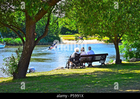 Vecchio folk su una panchina nel parco guarda le attività fluviale sul fiume Stour in Christchurch Quay nel Dorset Foto Stock