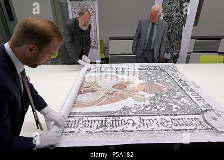 26 giugno 2018, Halle/Saale Germania: Michael Ruprecht (L-R), responsabile dell'archivio della Martin Luther University di Halle e il collettore Reinhard lampada da Amburgo, così come Kevin aringa dal London guardare uno sfregamento di Wilhelm Westval (1443-1509), vescovo di Lubecca la lapide presso l'università di Halle. Aringa e lampada sono considerati esperti nella zona di ottone di strisciamenti e sono attualmente contemplando donando loro collezioni personali all'università di Halle archivi. Si tratta di 600 strisciamenti dettagliata di lapidi provenienti da tutta la Gran Bretagna e la Germania. Le origini di sfregamento in ottone Foto Stock