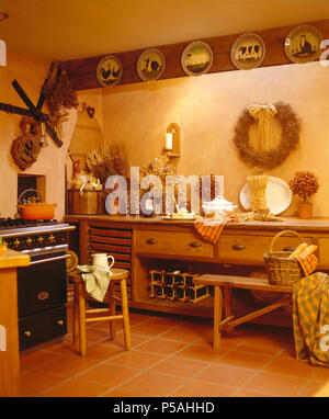 Sgabello di pino e panca in cottage cucina con raccolta di piastre di animale sulla trave di legno Foto Stock