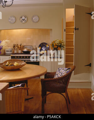 Vimini sedia in legno chiaro Tavolo in cottage cucina con porta aperta alla scalinata accanto al forno di gamma Foto Stock