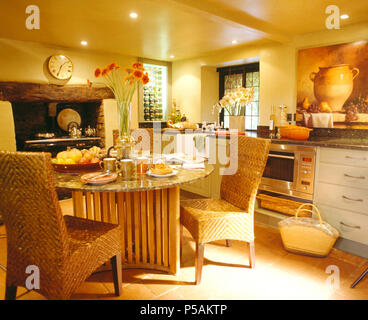 Tall-schienale intrecciato sedie di vimini in granito + legno tavolo da pranzo in cucina moderna con illuminazione verso il basso Foto Stock
