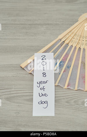Anno Nuovo Cinese design. Una busta rossa del denaro per il nuovo anno cinese isolato con una mano la ventola e una nota 2018 anno del cane Foto Stock
