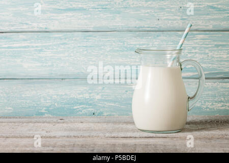 Brocca di vetro con il latte sul tavolo di legno Foto Stock